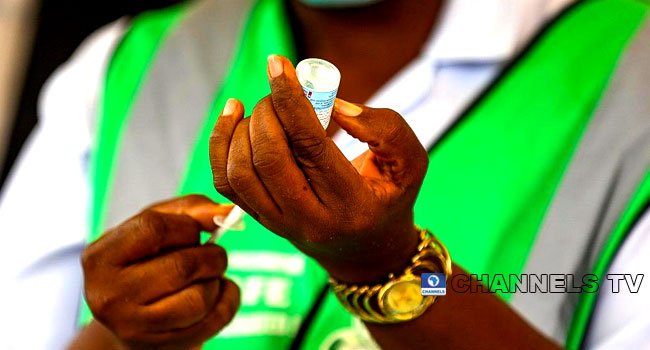 In this photo taken on August 16, 2021, a health official holds a vaccine tube and a syringe as Nigeria commences the second phase of COVID-19 vaccination. Channels TV/ Sodiq Adelakun.